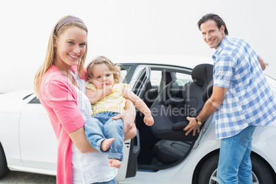 Parents carrying baby and her car seat