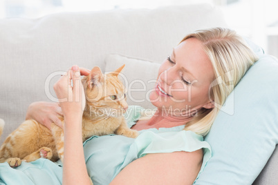 Woman stroking cat while lying on sofa