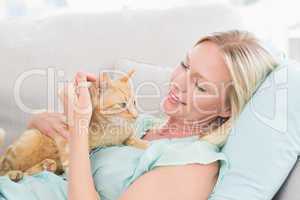 Woman stroking cat while lying on sofa