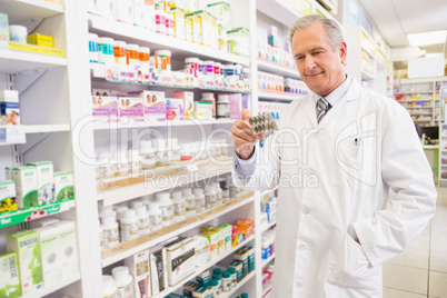 Smiling senior pharmacist holding blister