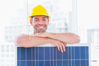 Smiling manual worker with solar panel in office