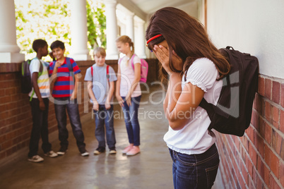 Sad schoolgirl with friends in background at school corridor