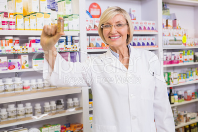 Smiling pharmacist showing medication at camera