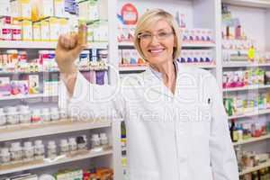 Smiling pharmacist showing medication at camera