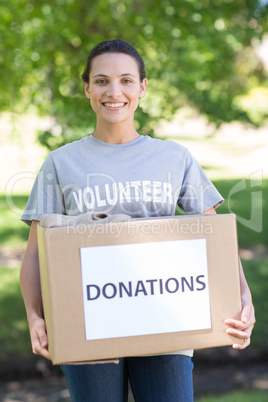 Pretty volunteer holding a donation box in park