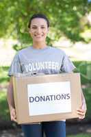 Pretty volunteer holding a donation box in park