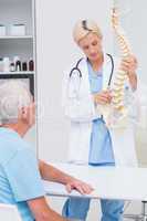 Doctor explaning spine model to patient in hospital