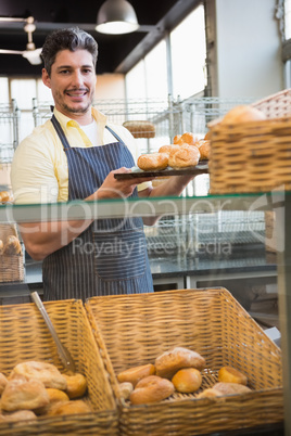 Smiling waiter showing tray of breads