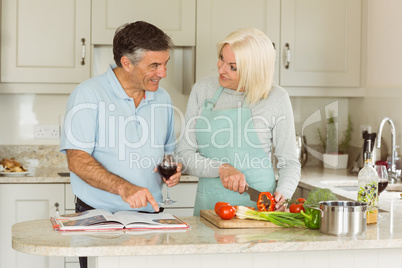 Happy mature couple having red wine while making dinner