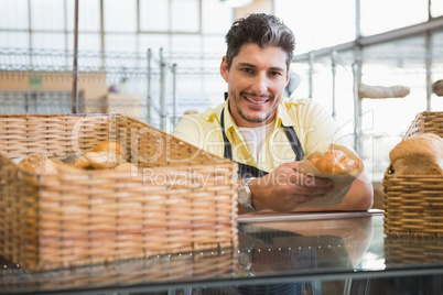 Smiling server in apron holding bread