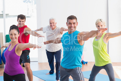 People doing warrior pose in yoga class