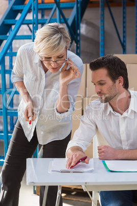 Focused warehouse team working together with clipboard