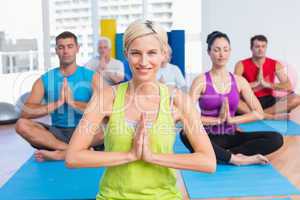 Woman with class meditating in fitness studio