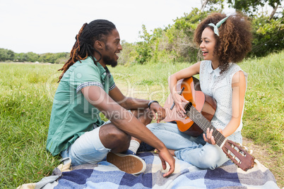 Young couple on a picnic playing guitar