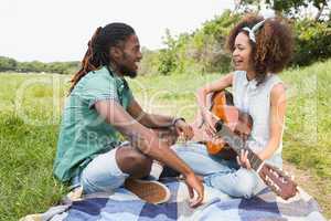 Young couple on a picnic playing guitar