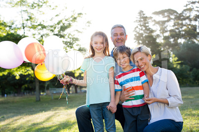 Happy family holding balloons at the park