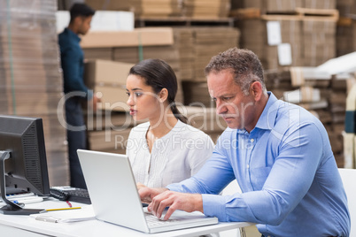 Warehouse managers working with laptop at desk