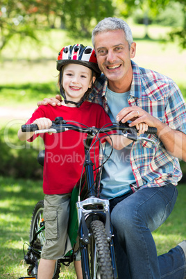 Happy little boy on his bike with his father