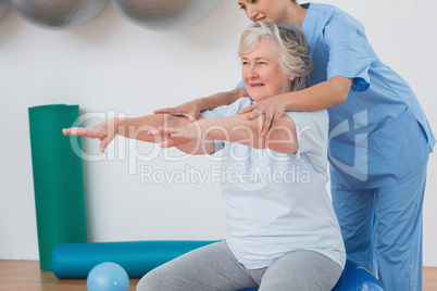 Instructor assisting senior woman to exercise