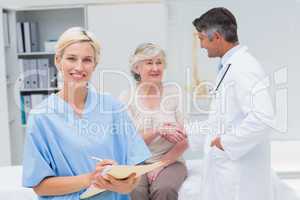 Nurse making reports while doctor and patient shaking hands