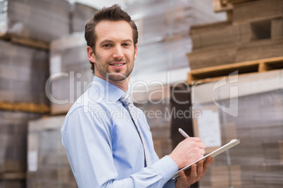 Handsome warehouse manager smiling at camera