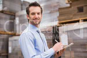 Handsome warehouse manager smiling at camera