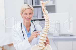 Female doctor with anatomical spine in clinic