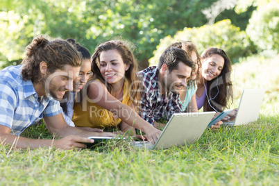 Smiling friends in the park using tablet pc and laptop