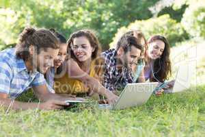 Smiling friends in the park using tablet pc and laptop