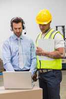 Warehouse worker and manager looking at laptop