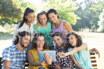 Smiling friends in the park using tablet pc