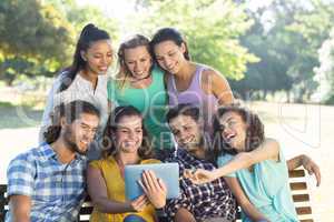 Smiling friends in the park using tablet pc