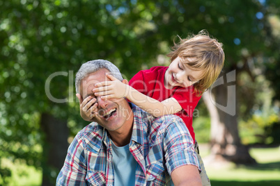 Happy little boy hiding his fatherss eyes with his hands