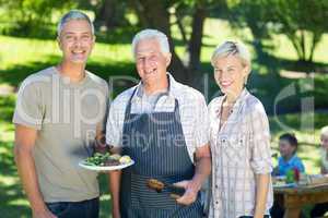 Happy couple with grandfather doing barbecue