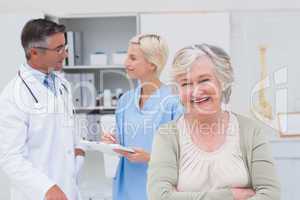 Patient smiling while doctor and nurse discussing in background