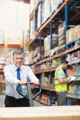 Manager pulling trolley with boxes in front of his employee