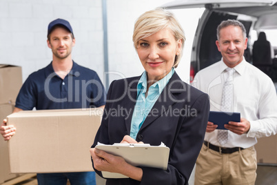 Smiling manager holding clipboard in front of his colleagues