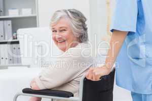 Senior patient in wheelchair being pushed by nurse