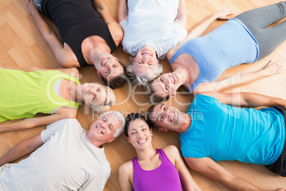 Happy people lying on hardwood floor at gym