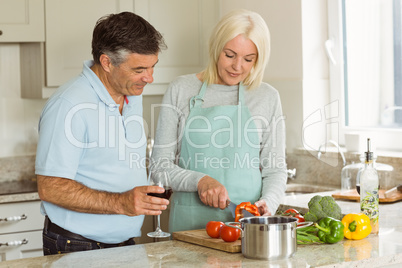 Happy mature couple having red wine while making dinner