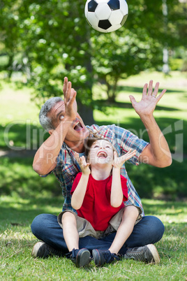 Happy father playing at the ball with his son