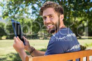 Young man using tablet on park bench