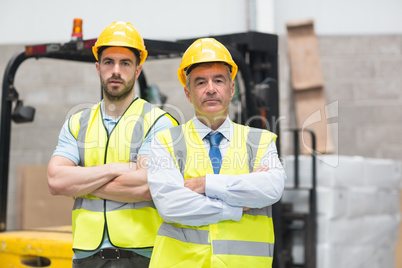 Manager with arms crossed and his colleague behind him