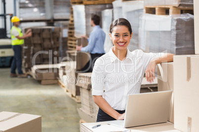 Smiling warehouse manager using laptop