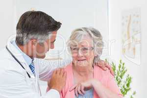 Doctor consoling senior patient in clinic