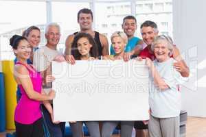 Happy people holding blank billboard at health club