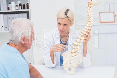 Doctor explaning spine model to senior patient