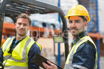 Smiling warehouse worker and forklift driver