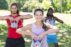 Fitness group working out in park with kettle bells