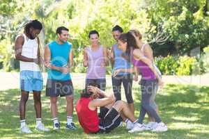 Fitness group encouraging man doing sit ups